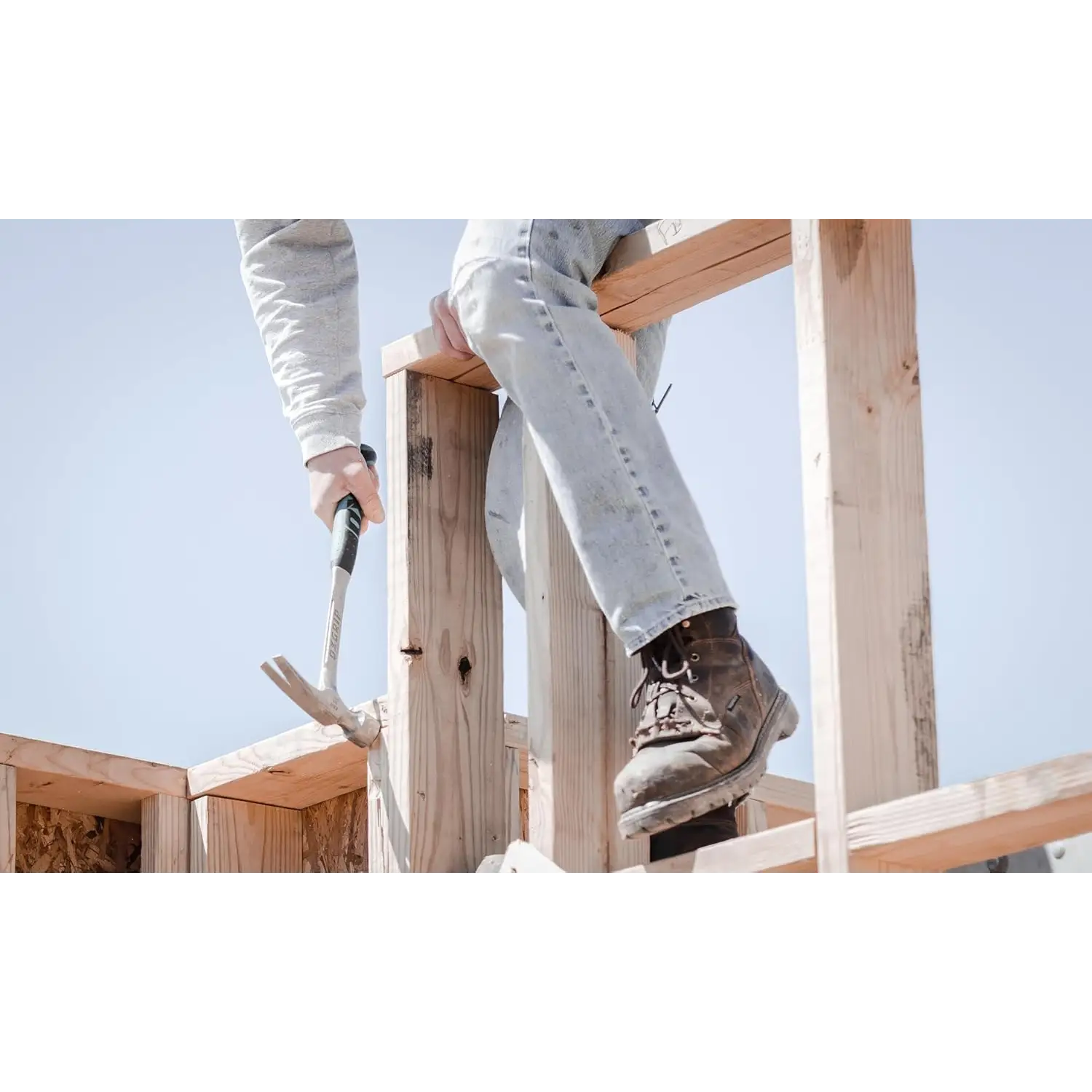 Persoană cu jeans și bocanci folosind ciocan dulgherie OX Pro otel forjat soft grip