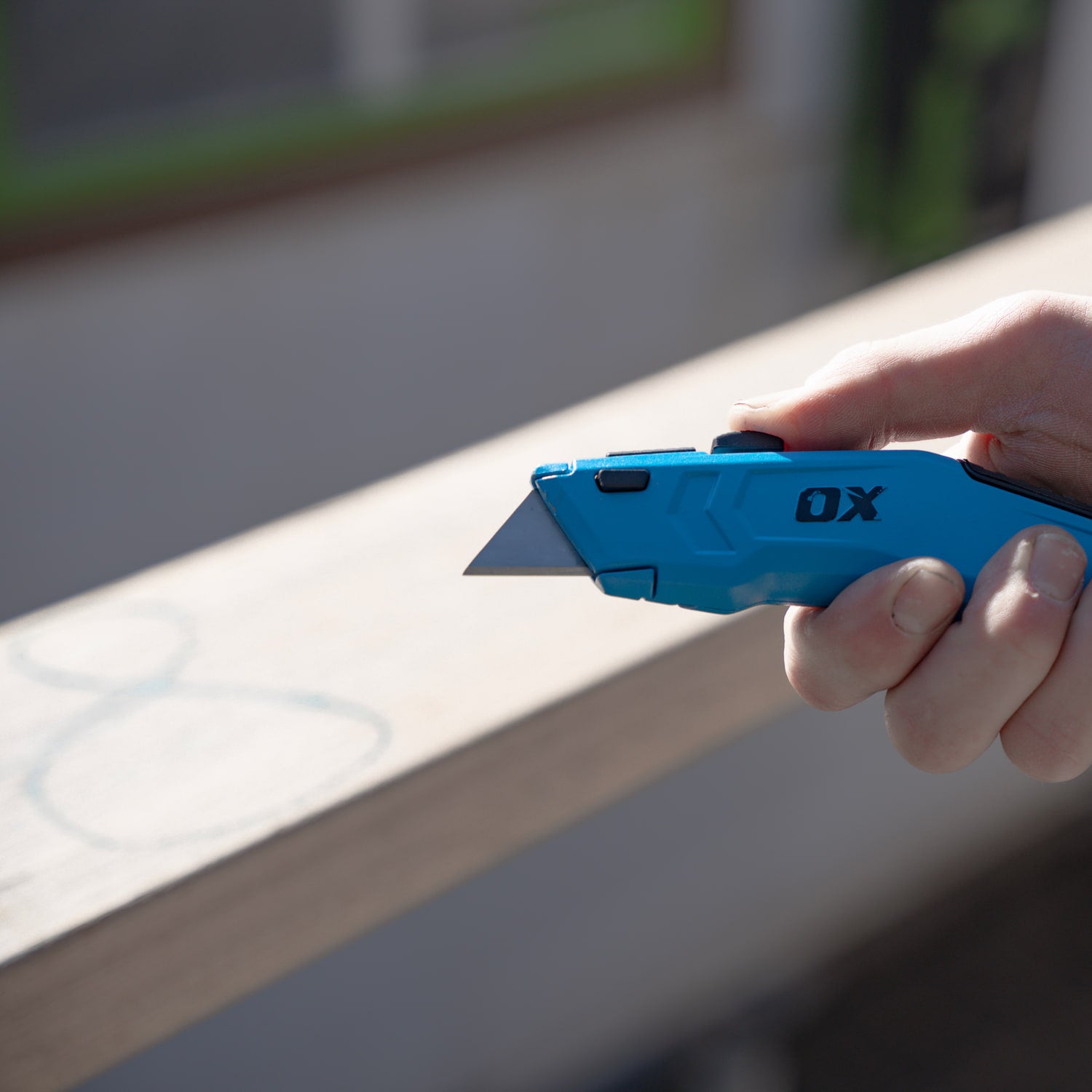 Cutter retractabil OX PRO ținut în mână, cu lama scoasă, pe șantier