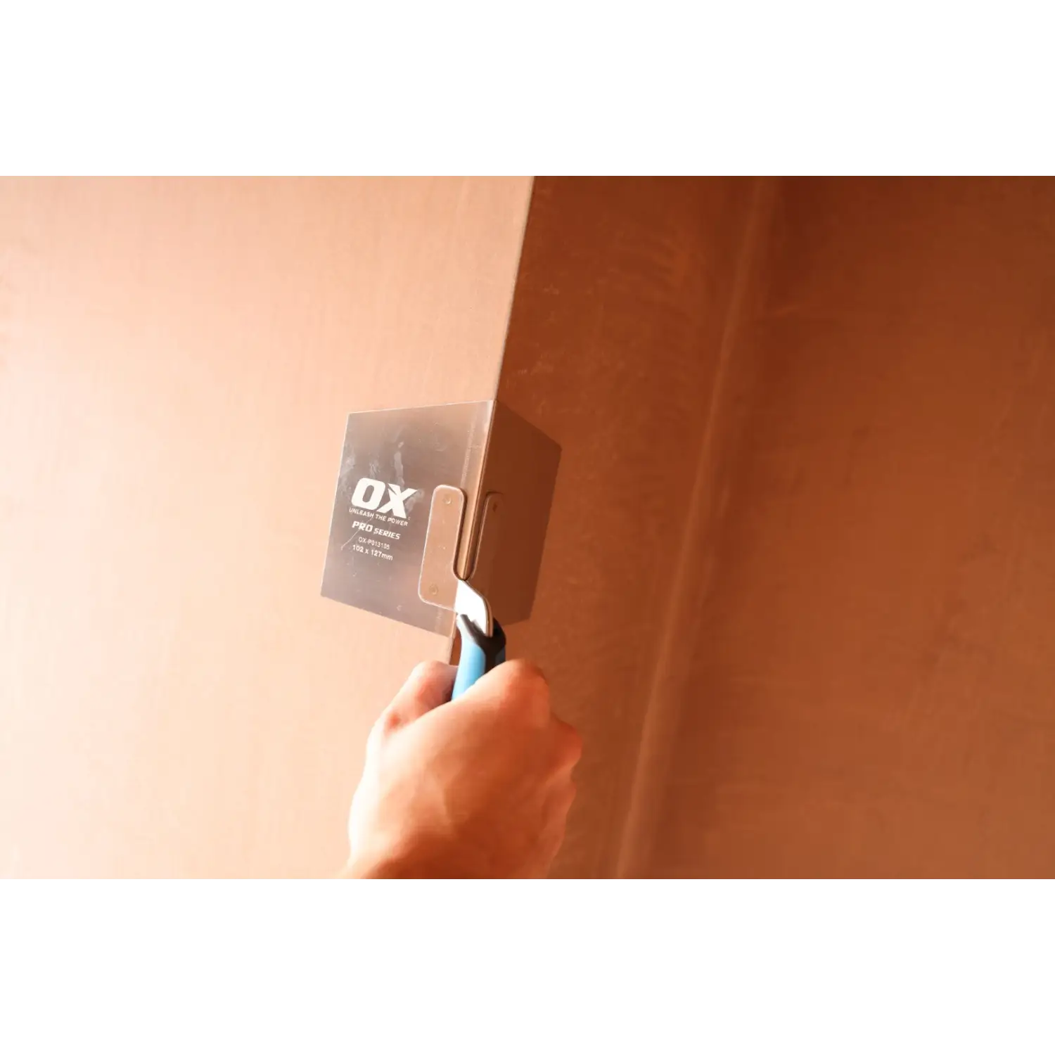 Mână ținând gletiera colt exterior inox flexibil pentru colturi exterioare durabile