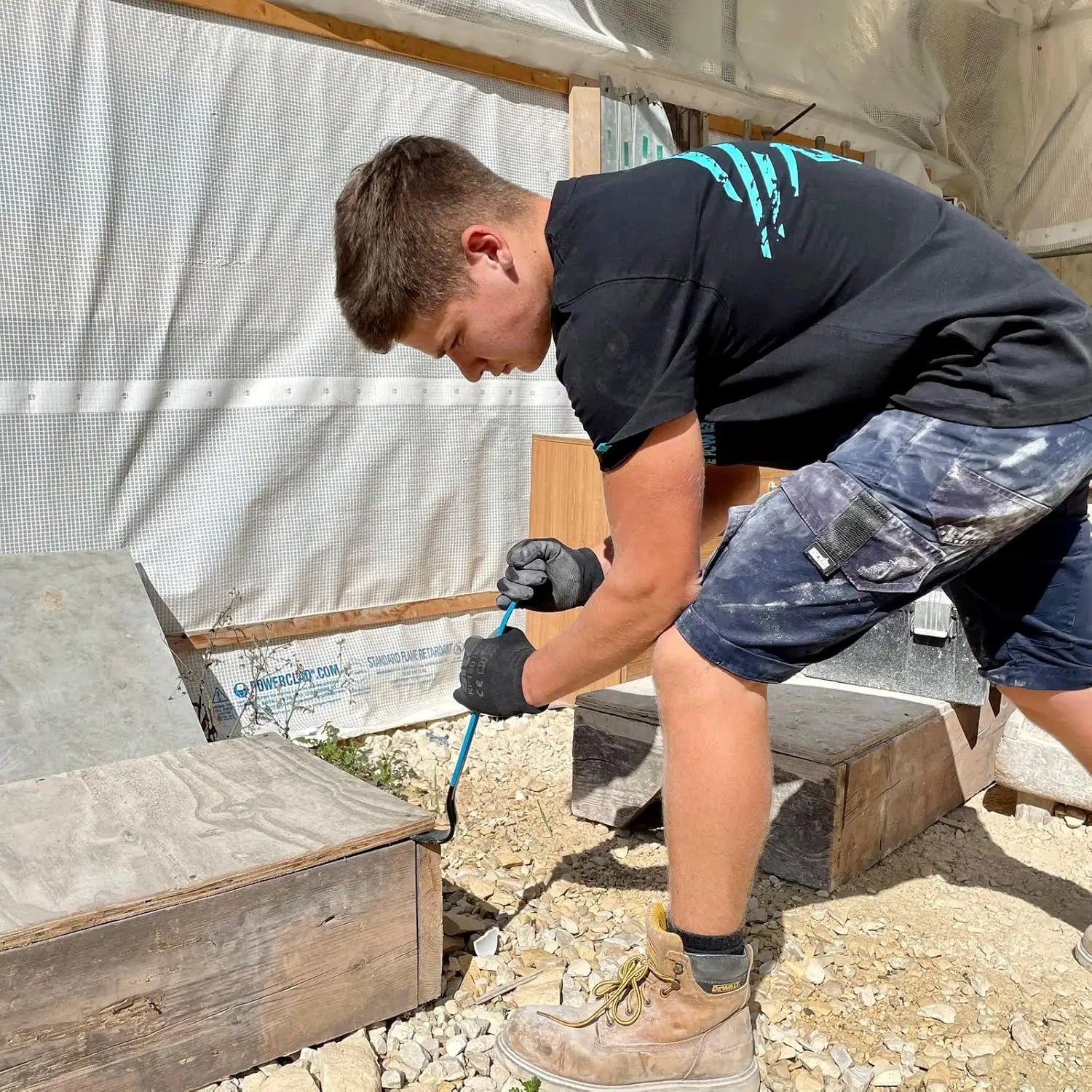 Tânăr muncitor cu mănuși folosind un levier de demolare OX Pro 380 mm din oțel forjat tratat termic și acoperire pulberi