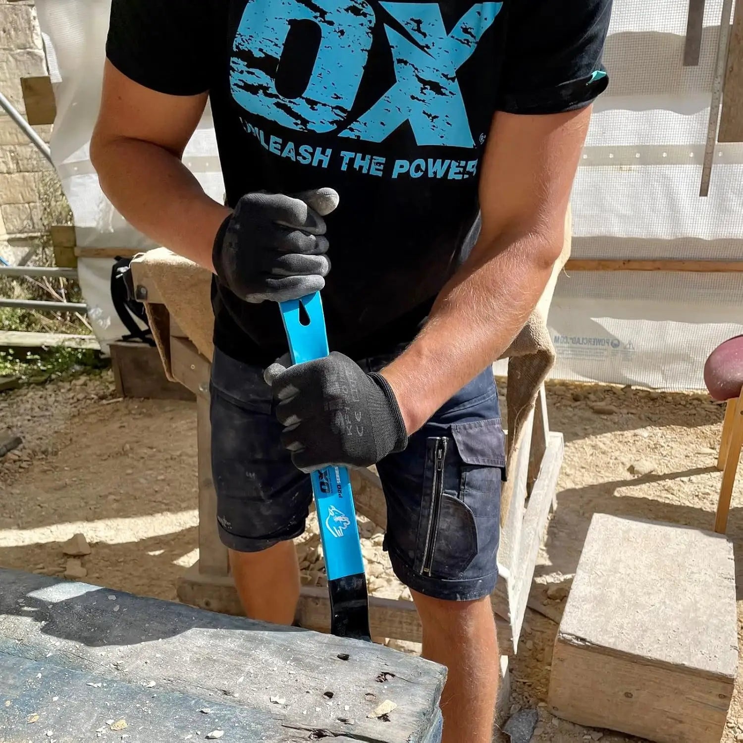 Persoană cu mănuși negre și tricou ox unleash the power ținând un levier de demolare otel forjat tratat termic acoperire pulberi