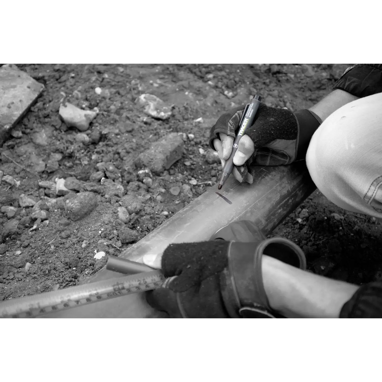 Mâini purtând mănuși marcând un țeavă metalică cu riglă și creion pentru ACF-BP1 Clog Free