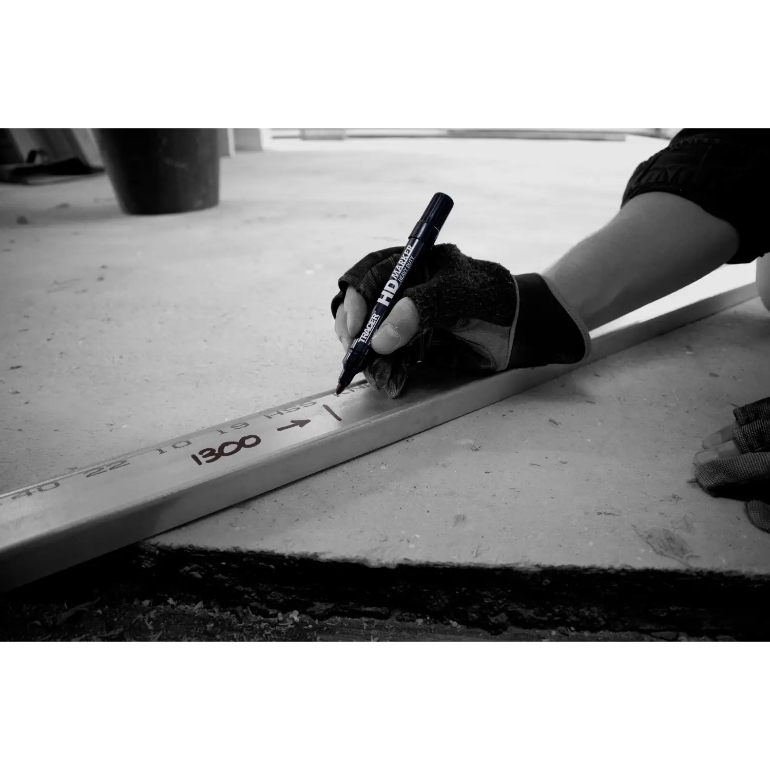 Mână cu mănușă scriind pe riglă cu marker tracer negru permanent și vârf durabil