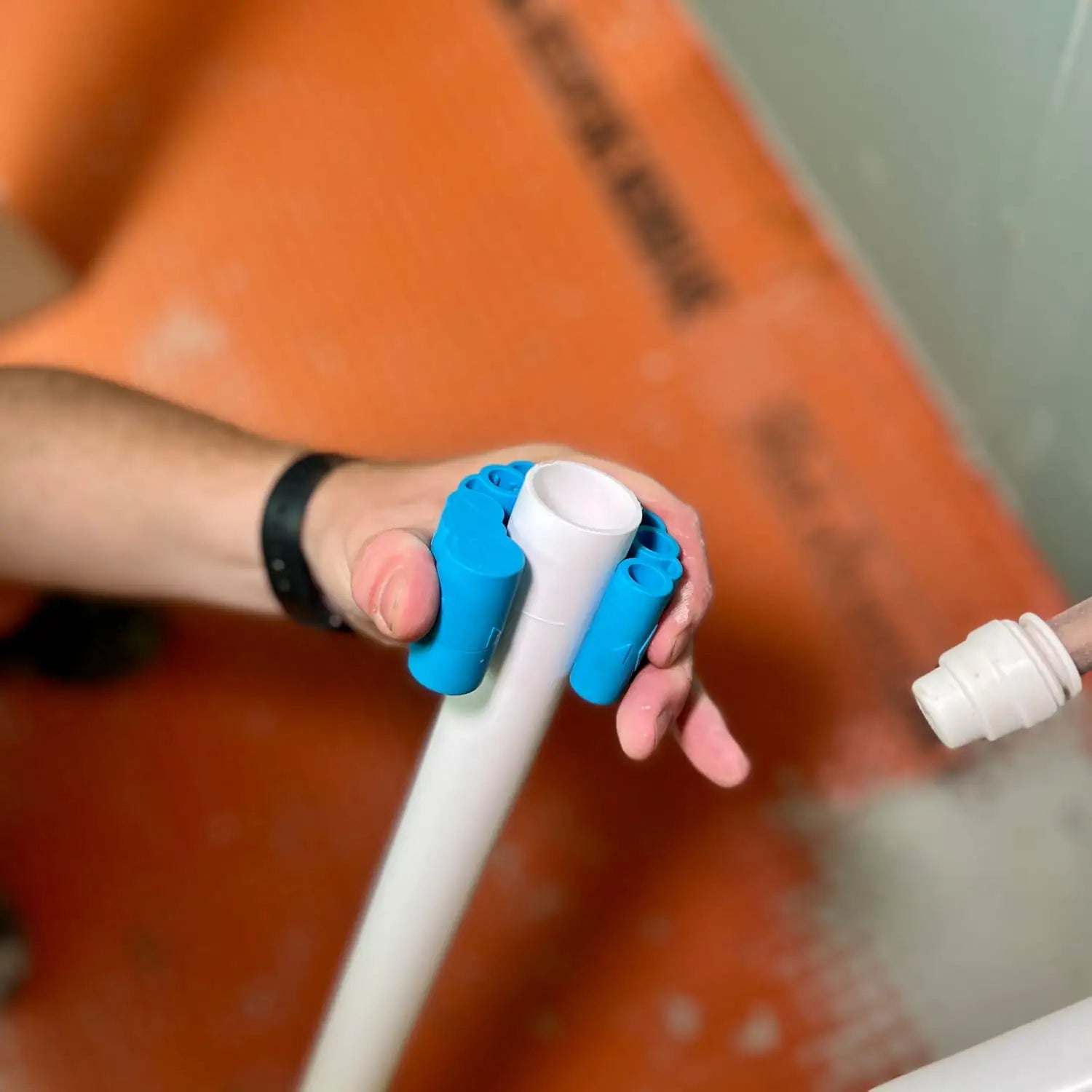 Mână ținând un tub PVC alb cu un instrument de deburring pentru tevi tuburi flexibile