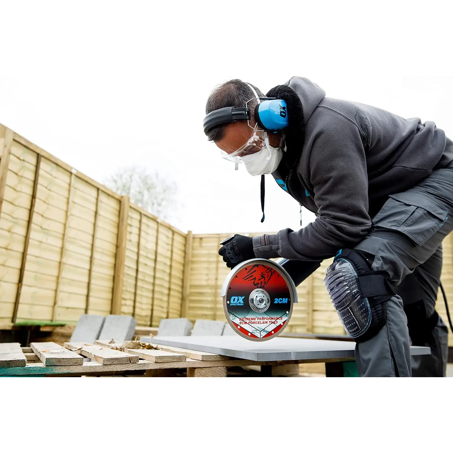 Persoană cu echipament de siguranță tăind o plăcuță cu disc diamantat OX Pro 2CM pentru portelan