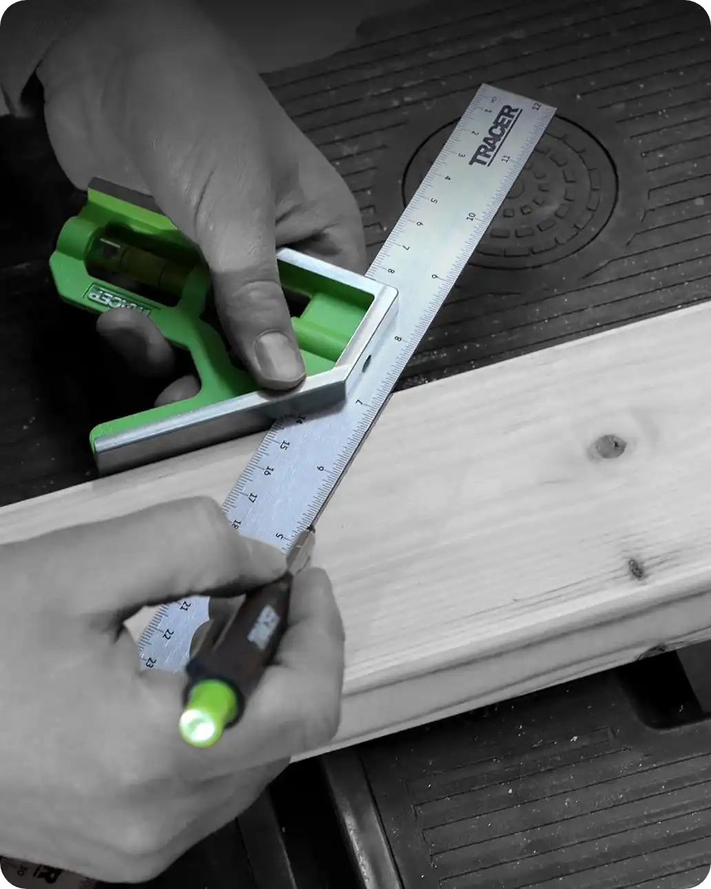 Mâinile unei persoane folosind un echer de combinație de culoare verde și un creion de marcaj pentru a trasa o linie pe o bucată de lemn.