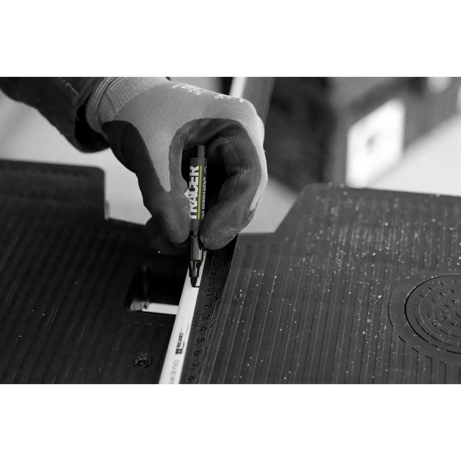 Mână cu mănușă de lucru ținând un markere permanente mini negre pe riglă