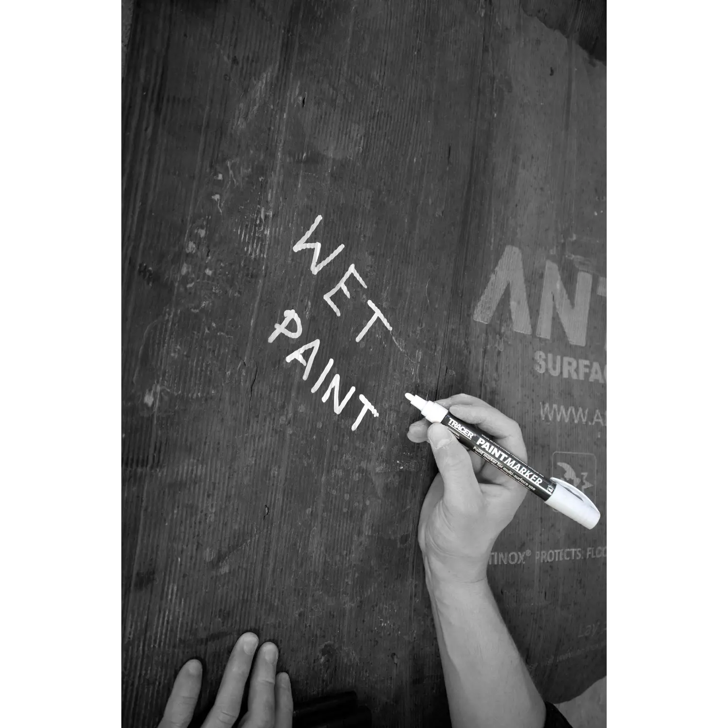 Imaginea arată scriere manuală WET PAINT cu markerul TRACER APTM2 pe lemn în construcții